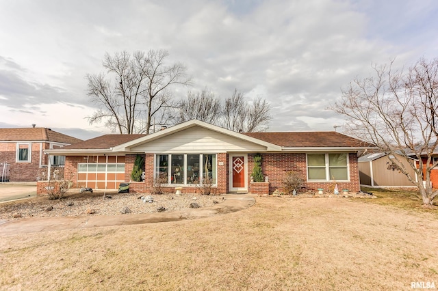 single story home featuring a storage shed, a front lawn, brick siding, and an outdoor structure