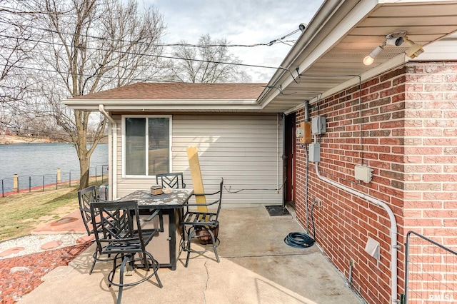 view of patio / terrace with a water view, outdoor dining space, and fence