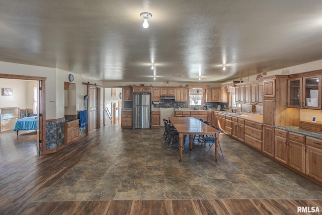 1548 Koehn Rd, Ava, IL 62907 - kitchen with freestanding refrigerator, under cabinet range hood, brown cabinets, and a barn door