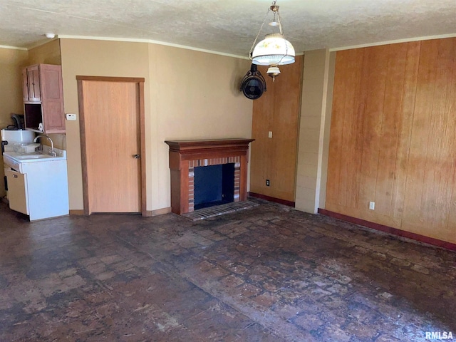 unfurnished living room with a textured ceiling, a brick fireplace, baseboards, and crown molding