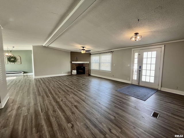 unfurnished living room featuring dark wood-style floors, a fireplace, visible vents, ornamental molding, and a textured ceiling