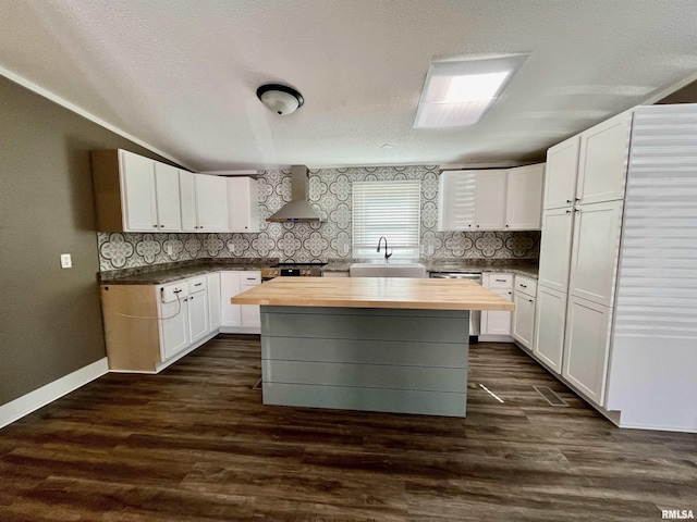 kitchen featuring dark wood-style floors, wall chimney exhaust hood, butcher block counters, and a sink