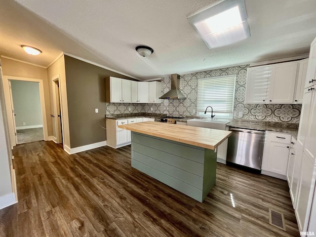 kitchen with dishwasher, butcher block counters, vaulted ceiling, wall chimney range hood, and a sink