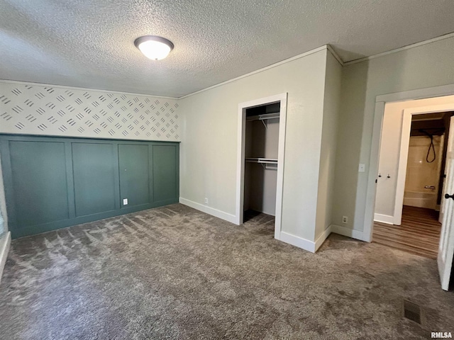 unfurnished bedroom with carpet floors, a closet, a decorative wall, and a textured ceiling