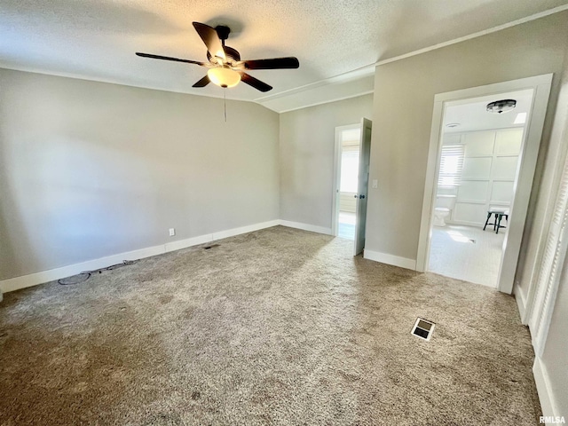 carpeted spare room featuring a textured ceiling, baseboards, visible vents, and a ceiling fan