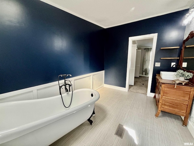 bathroom featuring wainscoting, a soaking tub, vanity, and a decorative wall