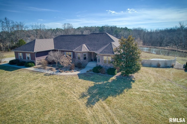 view of front of home featuring a front yard, stone siding, a water view, and roof with shingles