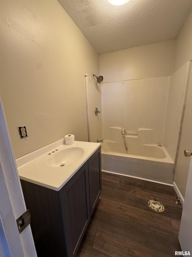 full bathroom with  shower combination, a textured ceiling, wood finished floors, and vanity