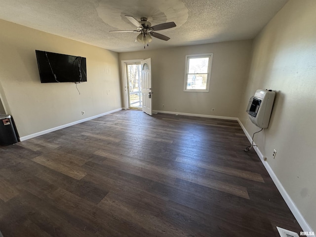 unfurnished living room featuring dark wood-style flooring, baseboards, a textured ceiling, and heating unit