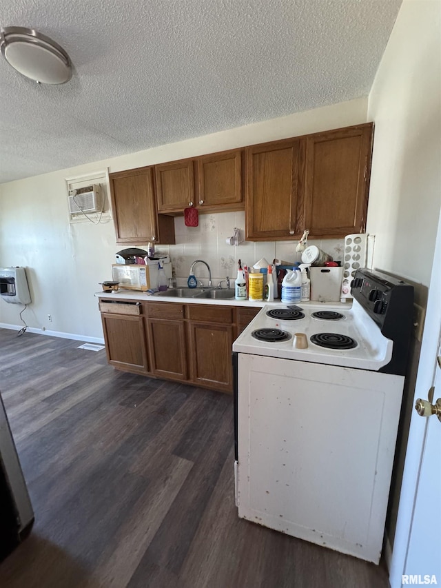 kitchen with a wall unit AC, white electric range, a sink, brown cabinetry, and dark wood finished floors