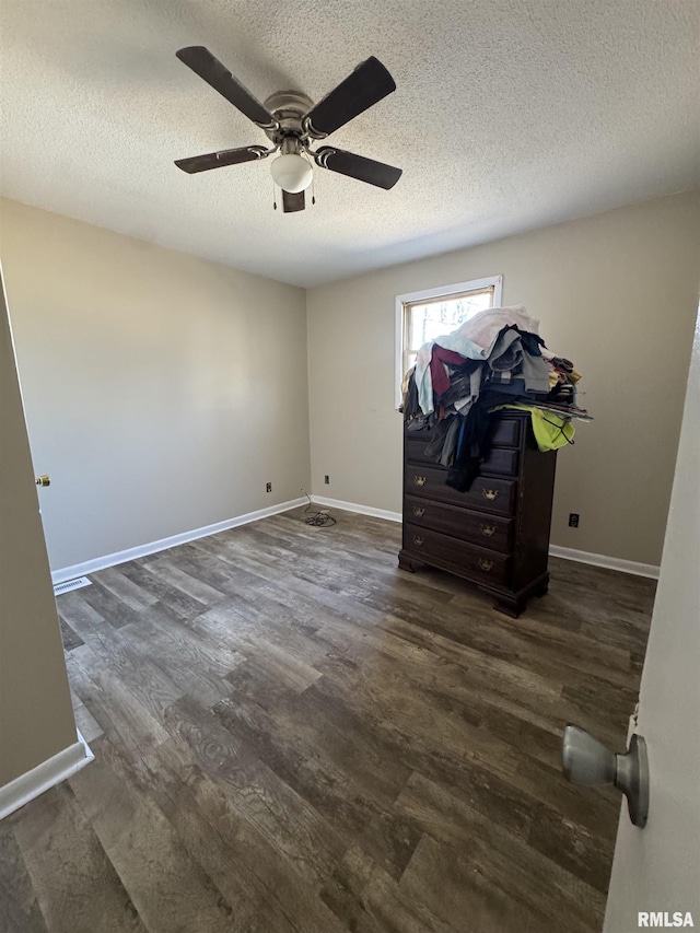 unfurnished bedroom with ceiling fan, a textured ceiling, baseboards, and wood finished floors