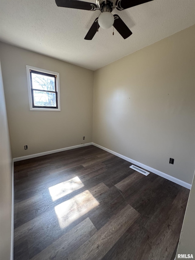 unfurnished room featuring a textured ceiling, dark wood-type flooring, visible vents, and baseboards