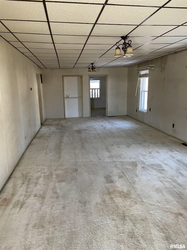 carpeted empty room featuring a drop ceiling