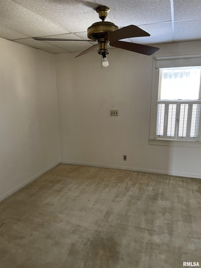 spare room with ceiling fan, a drop ceiling, carpet flooring, and baseboards