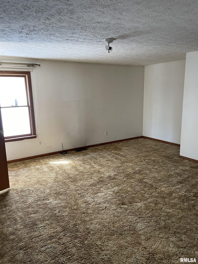 carpeted spare room featuring a textured ceiling and baseboards