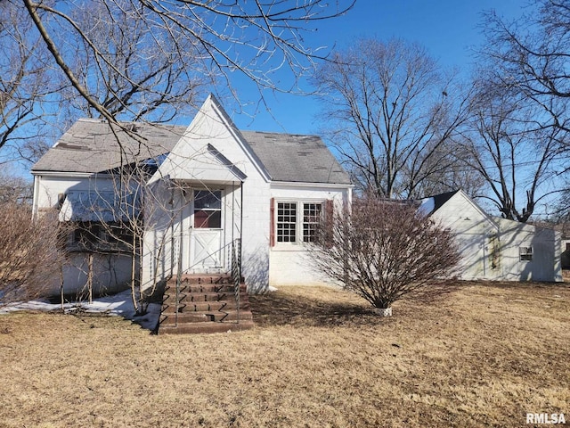 view of front facade featuring a front lawn and roof with shingles