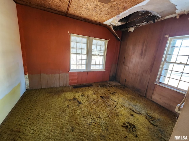 carpeted empty room with wooden walls