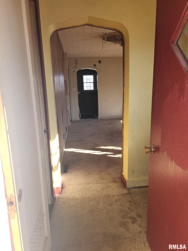 hallway featuring arched walkways and carpet floors