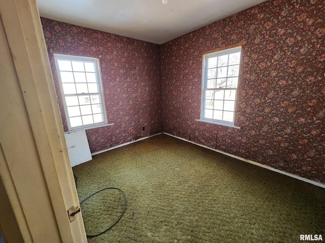 unfurnished room featuring dark colored carpet and baseboards