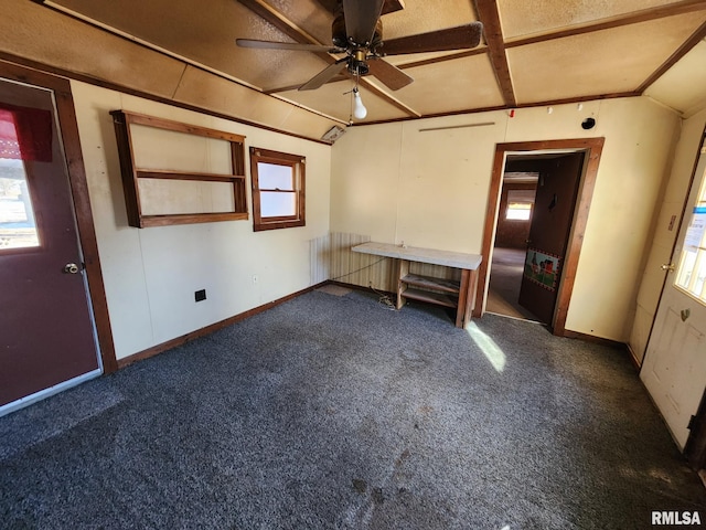 spare room featuring lofted ceiling, baseboards, dark colored carpet, and a ceiling fan