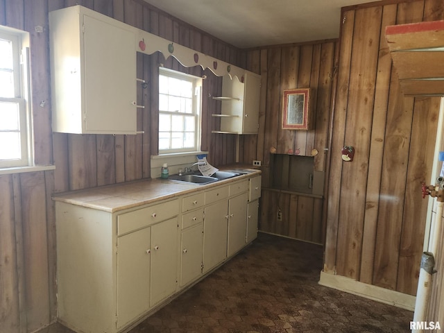 kitchen featuring open shelves, wood walls, a sink, and tile counters