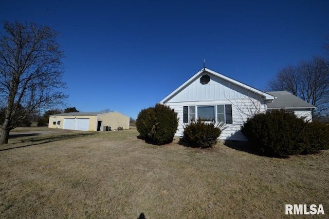 view of property exterior featuring a detached garage, a lawn, and an outdoor structure