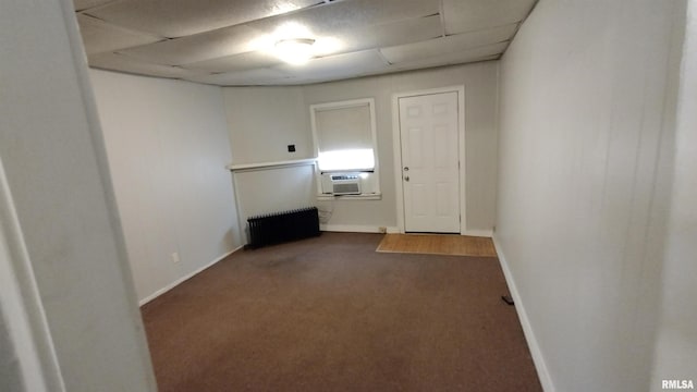 carpeted spare room featuring radiator, baseboards, and cooling unit