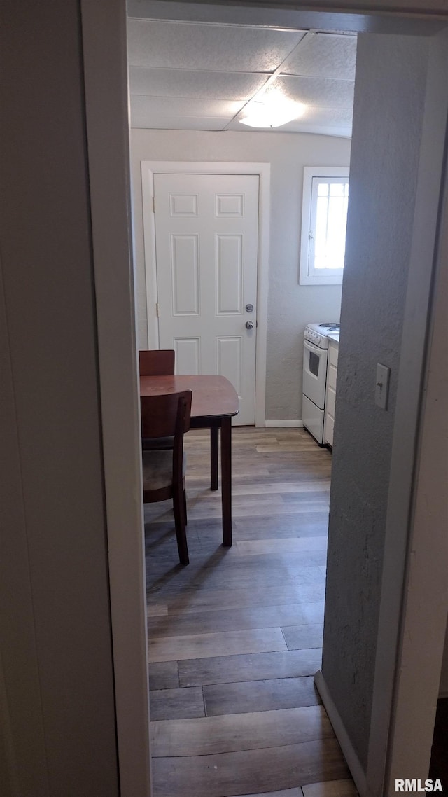 corridor with light wood-type flooring and baseboards