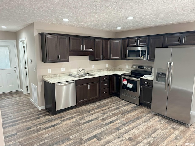 kitchen featuring light wood finished floors, light countertops, visible vents, appliances with stainless steel finishes, and a sink