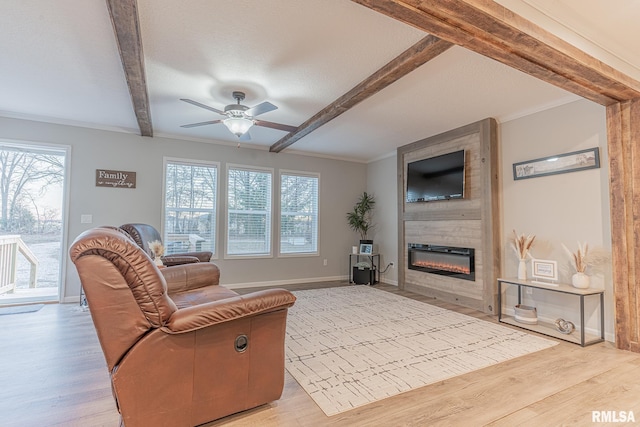 living area with beam ceiling, a large fireplace, light wood-style flooring, and baseboards