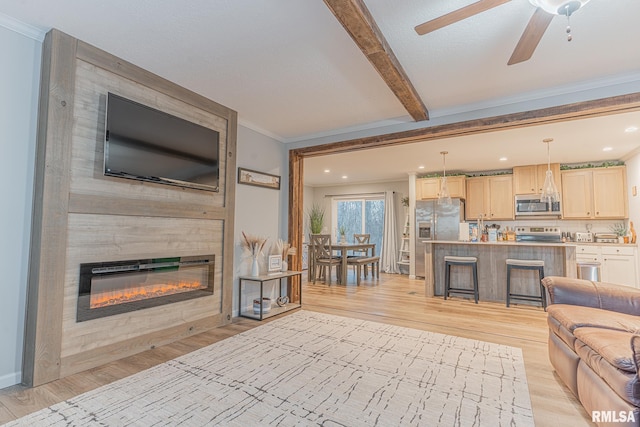 living room with crown molding, light wood-type flooring, a fireplace, beam ceiling, and recessed lighting