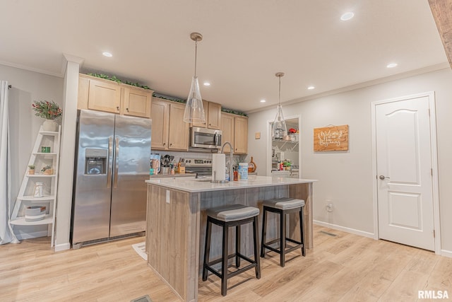 kitchen featuring stainless steel appliances, ornamental molding, light wood-type flooring, and a kitchen island with sink