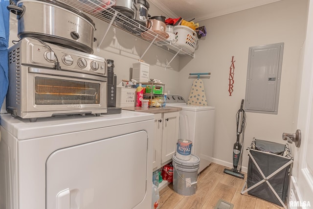 laundry room with cabinet space, light wood-style floors, ornamental molding, electric panel, and independent washer and dryer