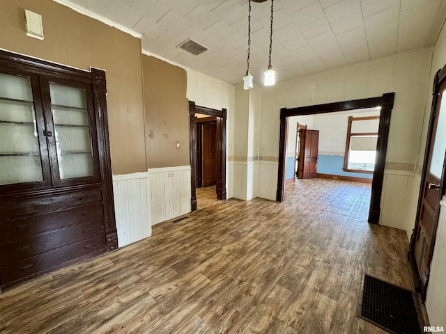 unfurnished room featuring wainscoting, visible vents, and wood finished floors