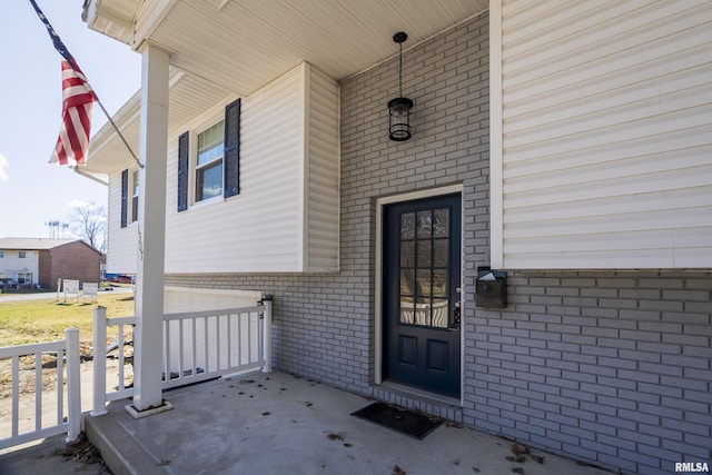 entrance to property featuring covered porch and brick siding