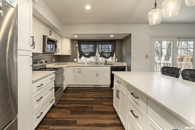 kitchen featuring dark wood-type flooring, a sink, white cabinetry, light countertops, and appliances with stainless steel finishes