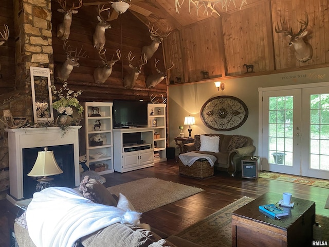 living room featuring high vaulted ceiling, dark wood-style flooring, a fireplace, french doors, and rustic walls