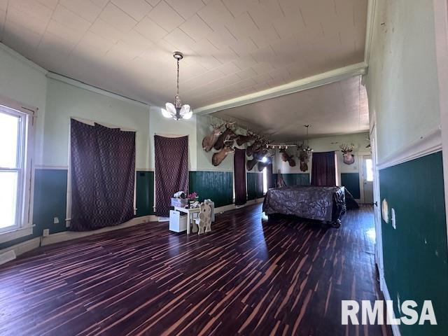unfurnished bedroom with a chandelier, wainscoting, and wood finished floors