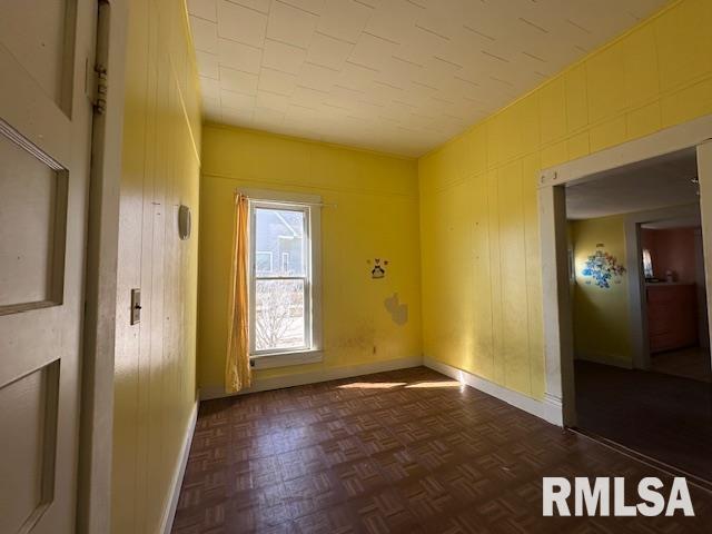 unfurnished room with baseboards and wooden walls