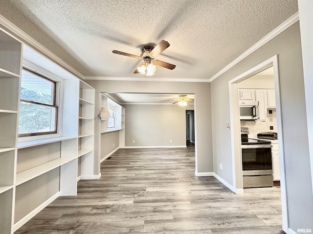 spare room with baseboards, a textured ceiling, wood finished floors, and crown molding