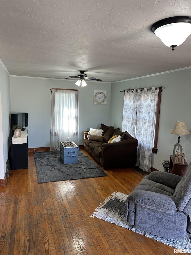 living area with a textured ceiling, hardwood / wood-style floors, crown molding, and baseboards