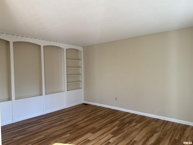 spare room with baseboards and wood finished floors