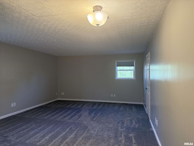 empty room with dark carpet, a textured ceiling, and baseboards