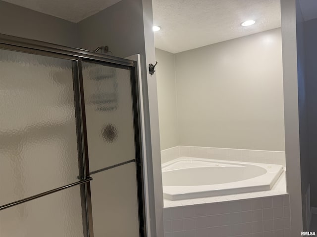 full bathroom featuring a textured ceiling, a shower stall, and a garden tub