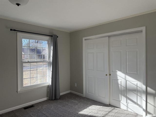 unfurnished bedroom featuring ornamental molding, dark colored carpet, multiple windows, and baseboards