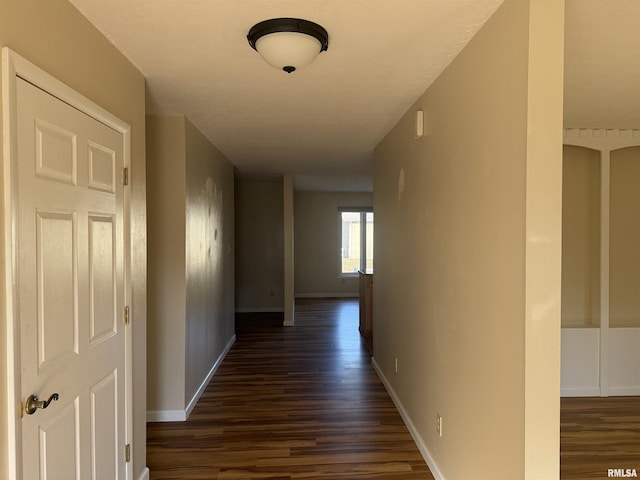 hallway with dark wood-type flooring and baseboards