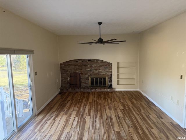 unfurnished living room with baseboards, built in features, a ceiling fan, wood finished floors, and a fireplace