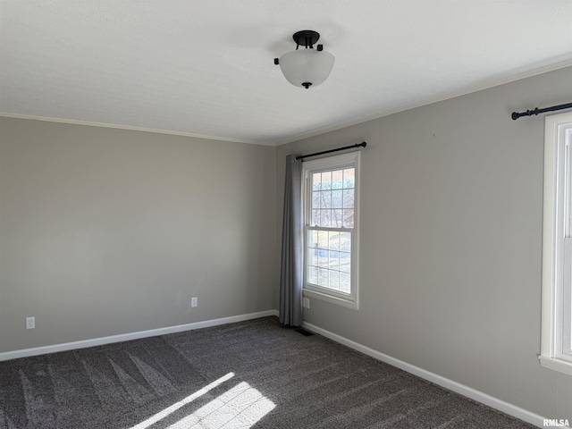 empty room with ornamental molding, dark carpet, and baseboards