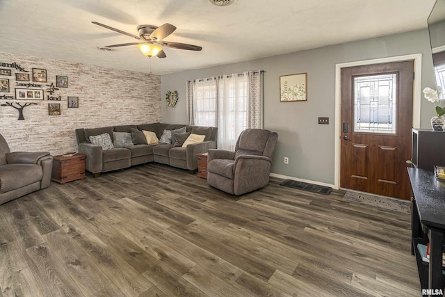 living area featuring baseboards, dark wood finished floors, and a ceiling fan