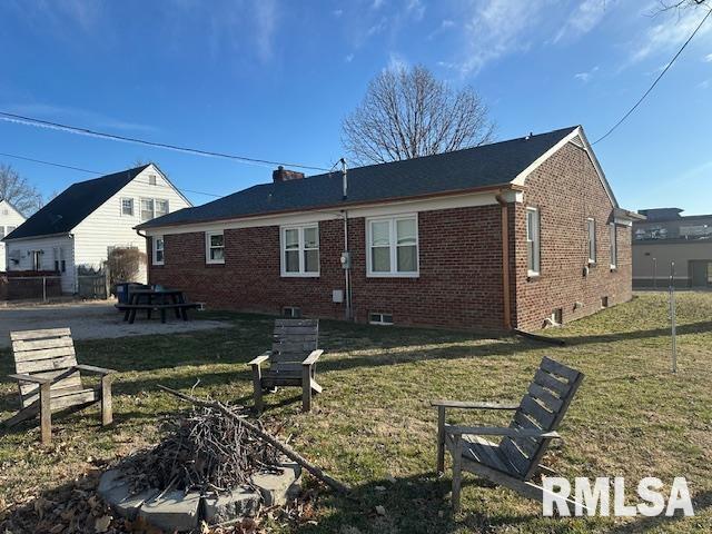 back of property featuring brick siding, a lawn, and a patio